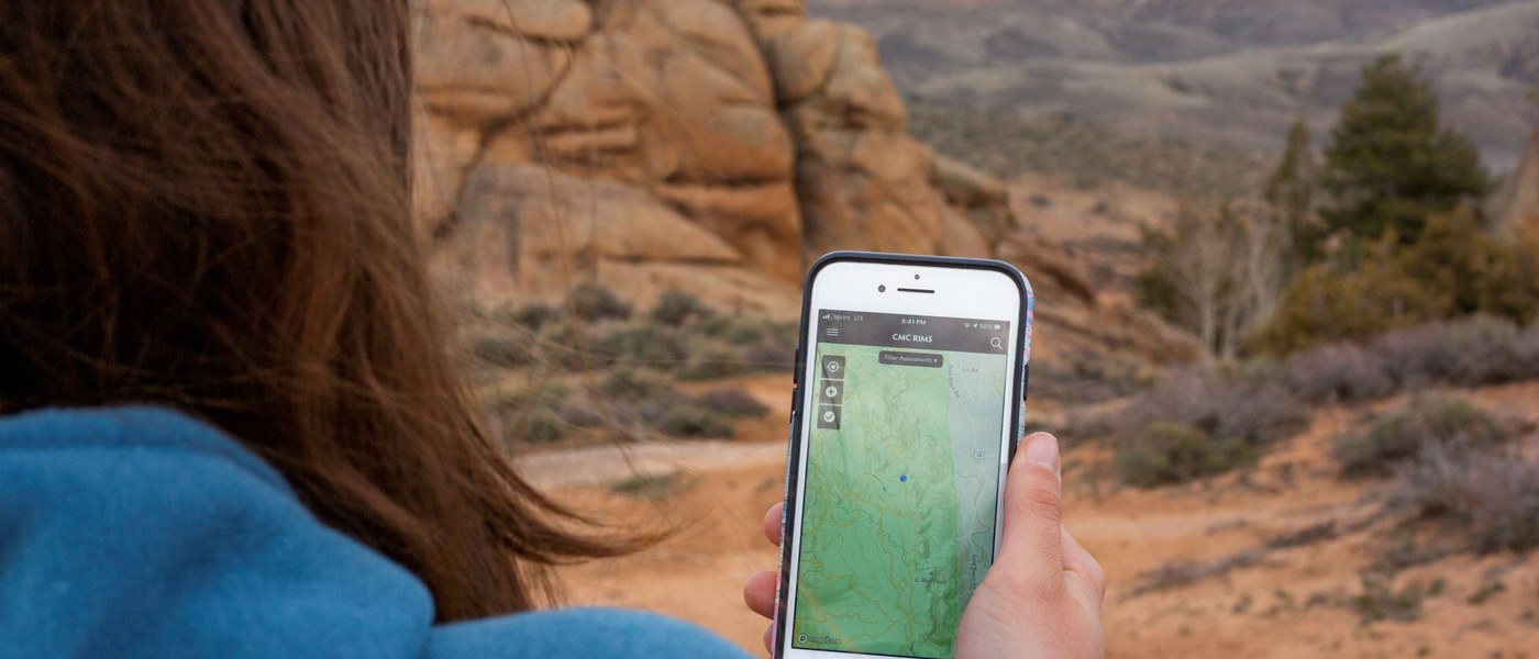 women looking at app on phone with canyon in background